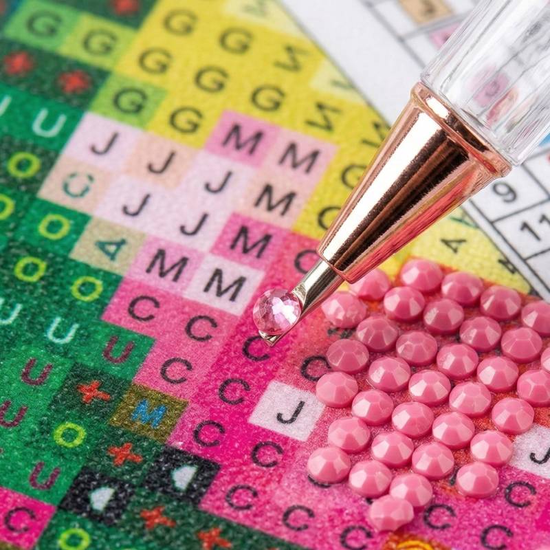 Close-up of the diamond painting applicator pen placing a sparkling resin gem on the canvas.