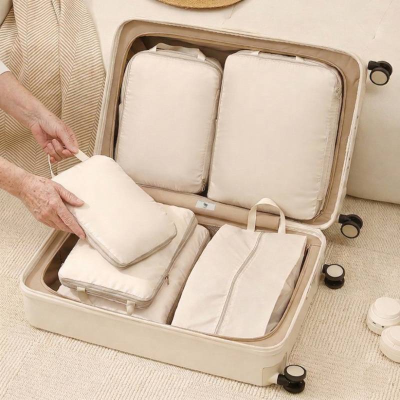 fully packed suitcase organized with beige compression cubes and a separate shoe bag