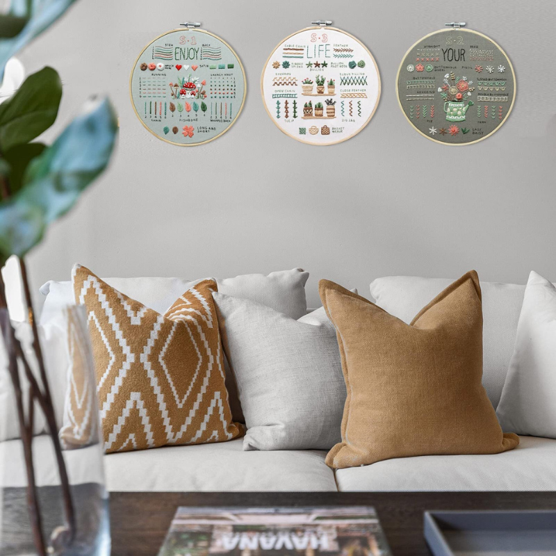 three finished stamped embroidery hoops displayed as stylish wall decor above a living room sofa
