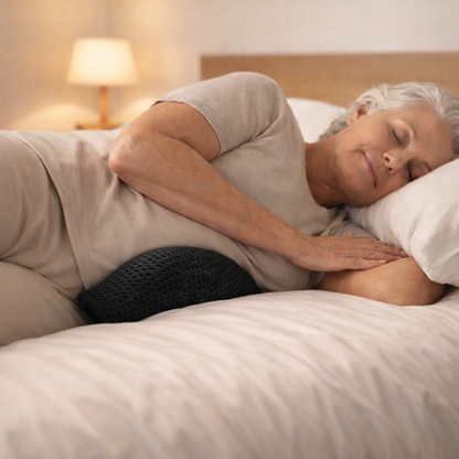 senior woman sleeping on her side with a lumbar pillow tucked under her waist for spinal alignment